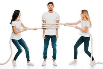 Obraz premium emotional young women holding rope around young man isolated on white