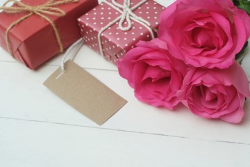 Elegant pink rose, gift box decorated with petals and card with natural soft light on wood...