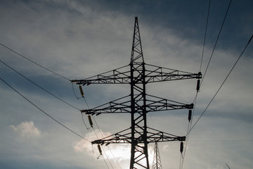 High voltage line against the blue sky. Electric main. Counterlight