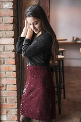 Fancy young woman brunette wearing trendy sparkling sequin skirt and a black blouse with sleeves and a cut on the chest