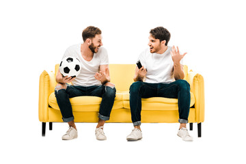 Obraz premium happy young men with soccer ball and remote controller looking at each other isolated on white