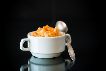 sweet boiled pumpkin porridge with rice in a plate on a black