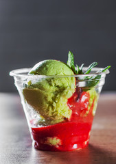 Green Organic Avocado Ice Cream and Strawberry Sorbet with red wine in a plastic cup with mint leaf