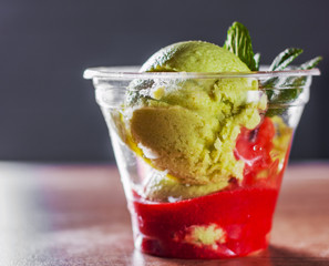 Green Organic Avocado Ice Cream and Strawberry Sorbet with red wine in a plastic cup with mint leaf