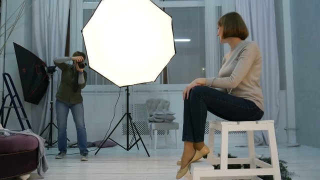 Studio photography. Young model poses for photographer in photo studio. Woman photographing teen girl. Backstage shot during indoor photoshoot.