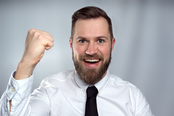 Happy business man celebrating and smiling isolated on grey studio background.