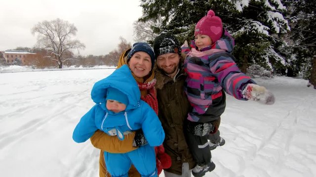 Young parents walking with their children in winter Park. Steadicam shot, slow motion, 4K