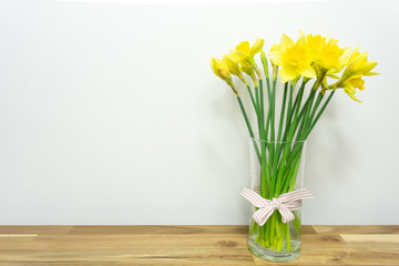 Bright yellow daffodils on wooden table with copy space