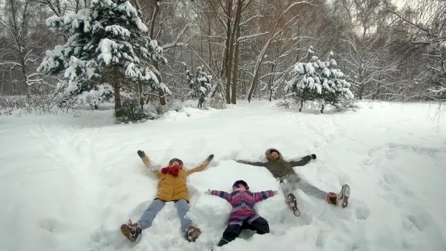 Family lying in snow. Steadicam shot, slow motion, 4K