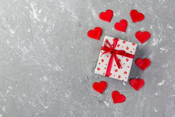 Valentine or other holiday handmade present in paper with red hearts and gifts box in holiday wrapper. Present box of gift on grey cement table top view with copy space, empty space for design