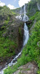 Fototapeta na wymiar High waterfall with a powerful stream falling from a cliff.