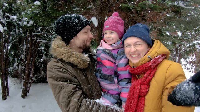 Attractive family having fun in winter park. Steadicam shot, slow motion, 4K
