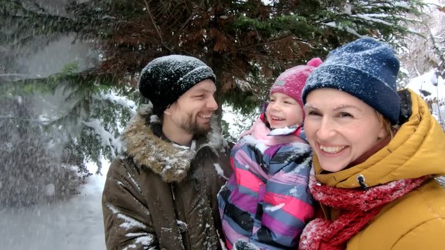 Attractive family having fun in winter park. Steadicam shot, slow motion, 4K