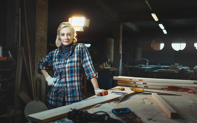 Beautiful middle aged woman worker posing against background of a woodworking workshop. Concept of motivated women, gender equality, image of femininity in modern world