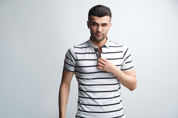 Attractive man in a striped polo shirt on a light gray background.