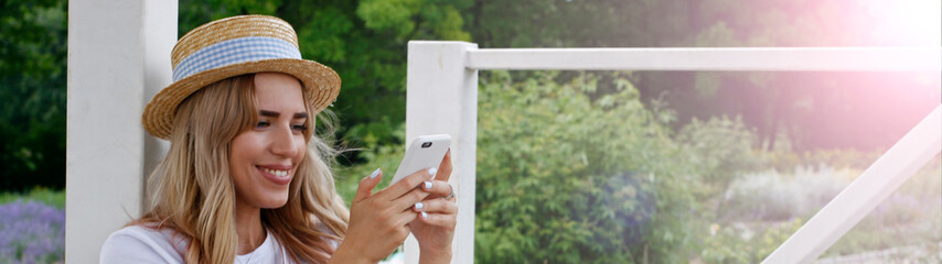 A girl with a charming smile in a straw hat makes a selfie on the phone