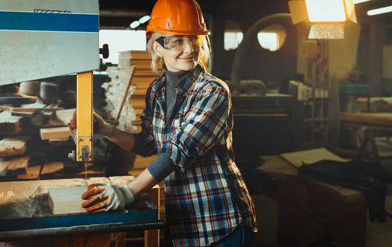 Middle aged woman working with a drill in workshop with copy cpace. Concept of woman in a male-dominated profession, nontraditional gender roles, gender equality, the image of femininity