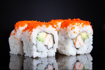 Four california rolls on black background