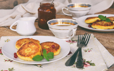 Frying cottage cheese pancakes with oat-flakes. Ukrainian or russian syrniki with jam and sour cream on wooden background. Traditional breakfast. Gluten free.