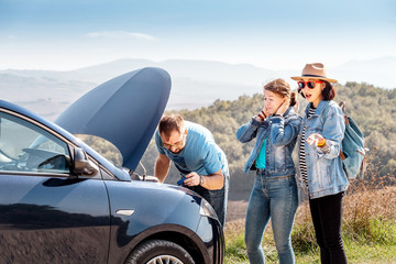 Group of friends having problems with broken car, while travelling by rental auto in Tuscany