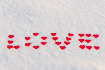 Vord love made of red hearts on the snow.