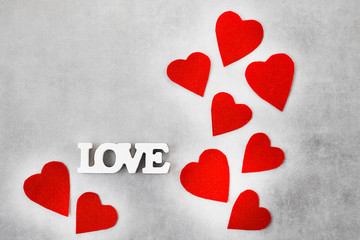 The word love of white letters and red decorative hearts on gray background. Valentine's Day...