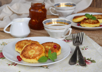 Frying cottage cheese pancakes with oat-flakes. Ukrainian or russian syrniki with jam and sour cream on wooden background. Traditional breakfast. Gluten free.