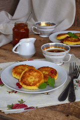 Frying cottage cheese pancakes with oat-flakes. Ukrainian or russian syrniki with jam and sour cream on wooden background. Traditional breakfast. Gluten free.