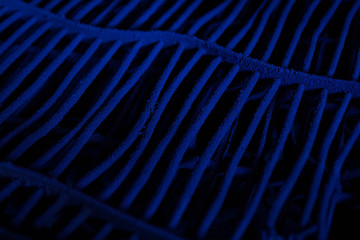 Blue wallpaper or background with blue grate made of metal covered with paint. Abstract blue background with black shapes. Symmetric lines in perspective.