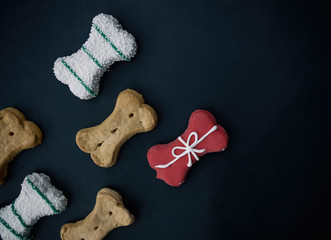 Decorative dog bone treats as flat lay on black background.