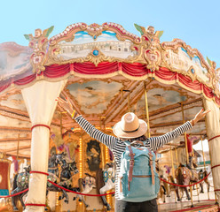 Happy asian woman traveler at the fairy carousel horses in amusement park