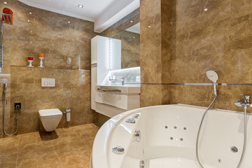 View of empty bathroom in brown and white colors with rounded ceramic bath,  bowl and other accessories, brown floor and big mirror.