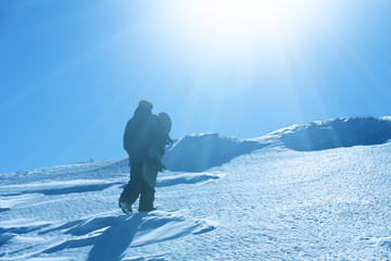 Snowboarder rises to the snowy peak for descent from the mountain. Freeriding
