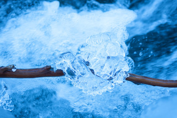 Bright blue glass crystal ice on river background. Macro, top view