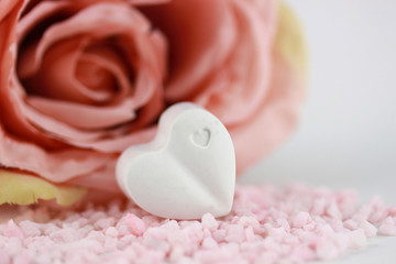 Obraz na płótnie Canvas Grusskarte - Herz in weiß auf Steine in rosa vor einer Rose in rose