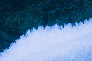 Natural pattern crystals hoarfrost, contrast ice flakes with turquoise water. Winter christmas background
