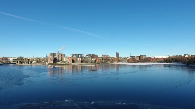 Aerial view over a partly frozen lake towards city skyline