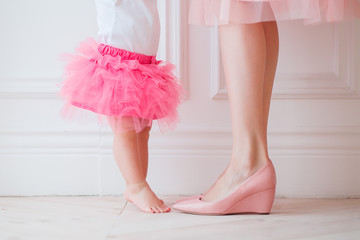 Mother's legs and daughters in pink skirts. My daughter is trying to put her legs to her mother. Legs girls and women. mother holds daughter in her arms