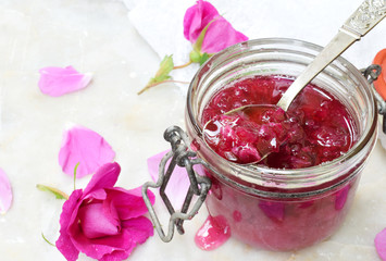 Jam of tea rose petal in glass jar on light marble background. Flower confiture. Healthy food. Copy...