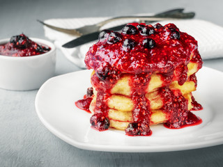 Pancakes or fritters with raspberry and blackcurrant jam, delicious dessert for breakfast.