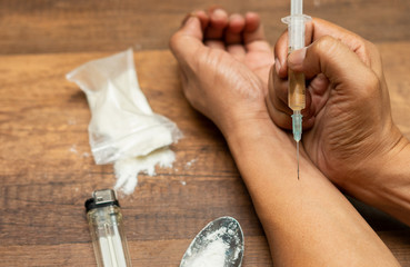 Drugs concept. Disease concept. Drug addict man with syringe using drugs.Dark theme, young guy very...