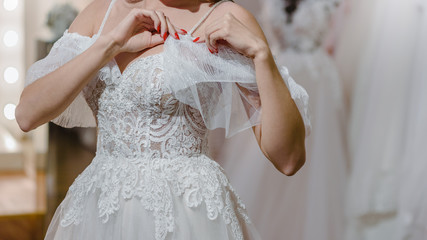 Closeup of bride correcting lace on her wedding dress