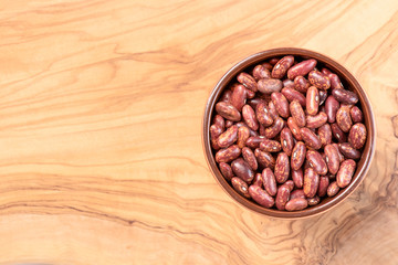 Pinto beans in a cup on olive wooden deck top view