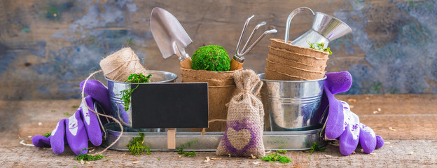 Gardening tools, pots and utensils on rustic wooden background, with a chalk board