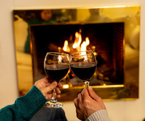 Close up of happy couple drinking wine by fire place celebrating love and winter holidays vacation