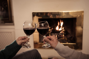 Close up of happy couple drinking wine by fire place celebrating love and winter holidays vacation