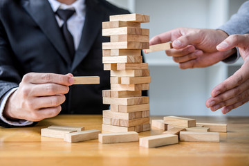 Images of hand of businesspeople placing and pulling wood block on the tower, Alternative risk concept, plan and strategy in business, Risk To Make Business Growth Concept With Wooden Blocks