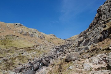 Fototapeta na wymiar Fast mountain stream tumbling between cliffs in a valley (Lake District, UK)