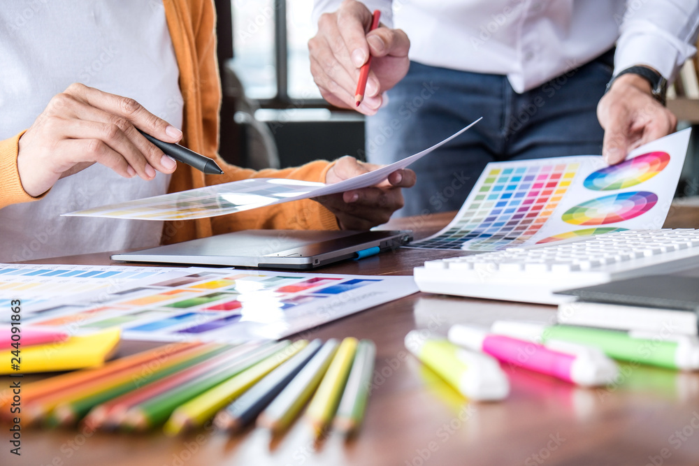 Poster Two colleagues creative graphic designer working on color selection and drawing on graphics tablet at workplace