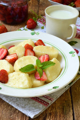 Sweet lazy pierogi. Ukrainian dumplings with sour cream, butter and strawberry on wooden background. Summer berry breakfast. Italian gnocchi. Copy space